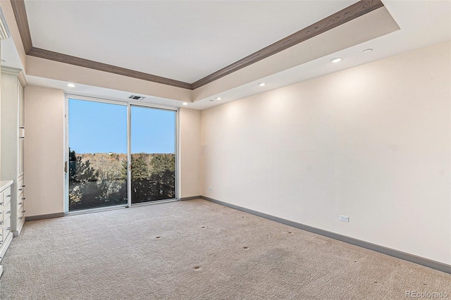 carpeted spare room with a tray ceiling and ornamental molding