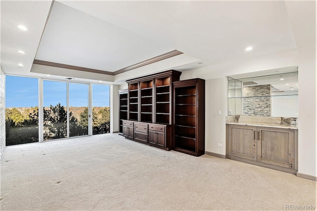 unfurnished living room featuring light carpet, crown molding, and a tray ceiling