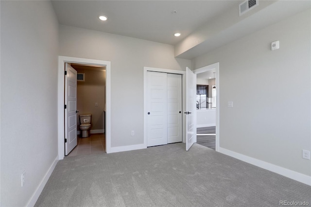 unfurnished bedroom with a closet, connected bathroom, and carpet flooring