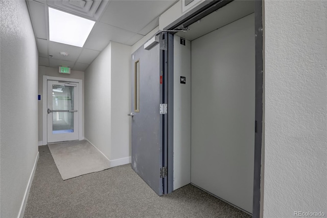 corridor featuring carpet floors, a paneled ceiling, and elevator