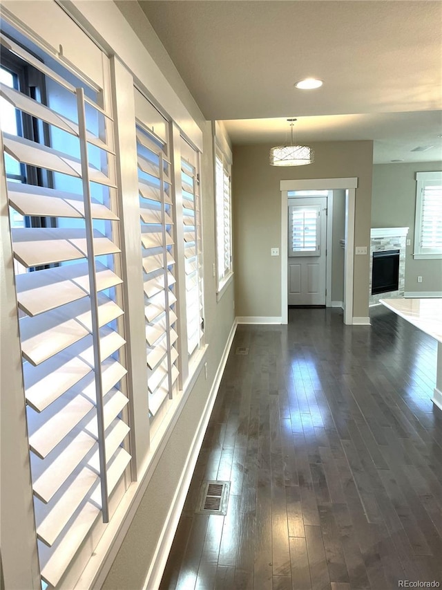 hall with a wealth of natural light, dark hardwood / wood-style flooring, and a notable chandelier