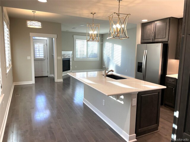 kitchen featuring pendant lighting, a center island with sink, sink, stainless steel refrigerator with ice dispenser, and dark brown cabinets