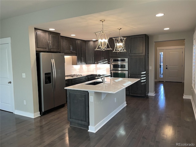 kitchen with sink, a chandelier, decorative light fixtures, a kitchen island with sink, and appliances with stainless steel finishes