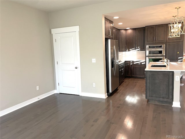 kitchen with sink, hanging light fixtures, dark hardwood / wood-style floors, stainless steel appliances, and a chandelier