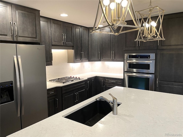 kitchen featuring light stone countertops, appliances with stainless steel finishes, tasteful backsplash, sink, and a notable chandelier