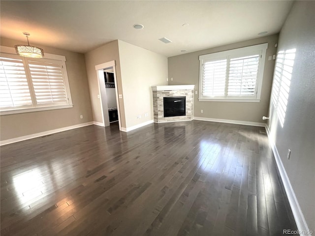 unfurnished living room with dark hardwood / wood-style floors and a stone fireplace