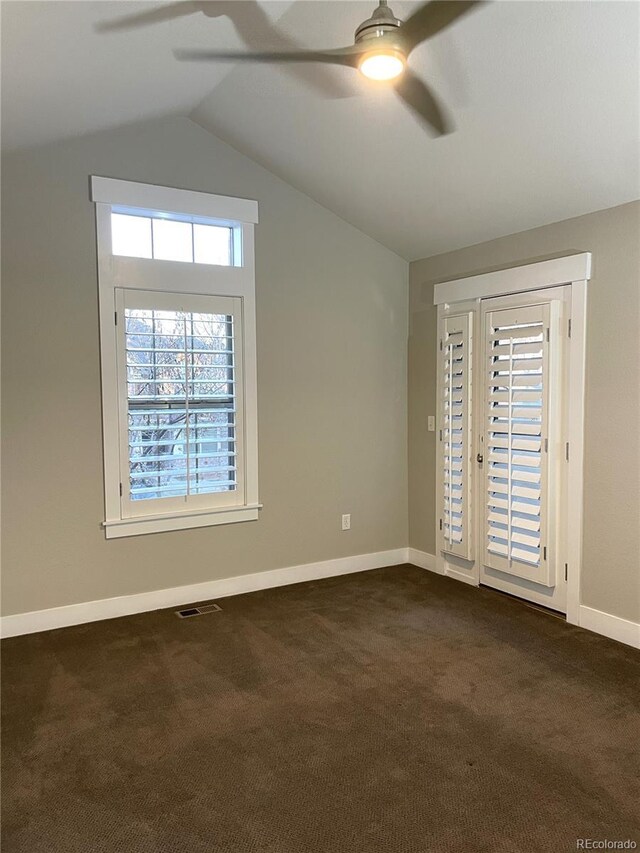 spare room featuring ceiling fan, dark carpet, and vaulted ceiling