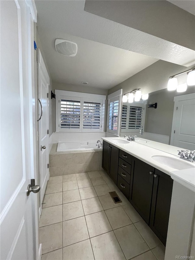 bathroom with tile patterned flooring, vanity, and tiled tub