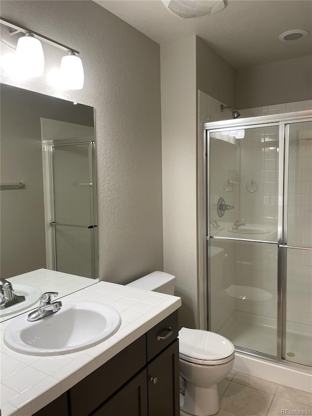 bathroom featuring tile patterned flooring, vanity, toilet, and a shower with door