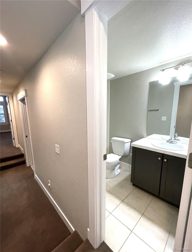 hallway featuring a textured ceiling, light tile patterned flooring, and sink