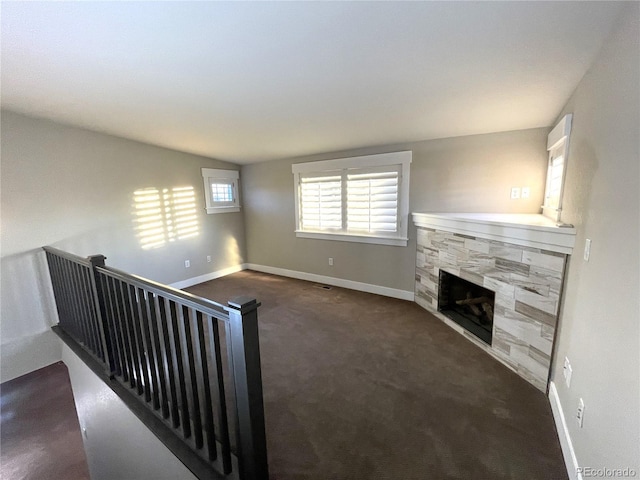 unfurnished living room featuring dark carpet, lofted ceiling, and a fireplace