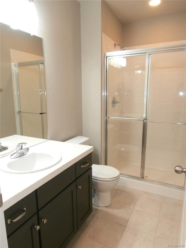 bathroom with tile patterned flooring, vanity, toilet, and an enclosed shower