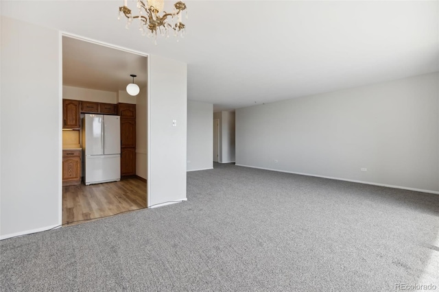 unfurnished living room featuring light carpet and a chandelier