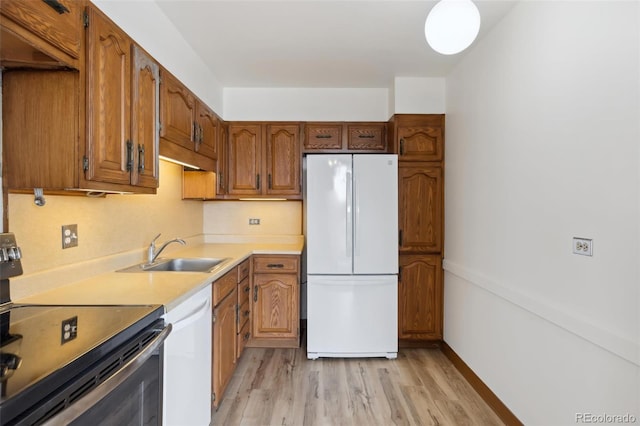 kitchen featuring sink, light hardwood / wood-style floors, and white appliances