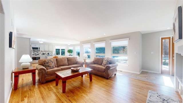 living room with recessed lighting, baseboards, a healthy amount of sunlight, and light wood finished floors