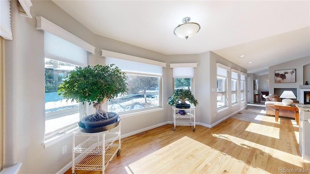 interior space with a fireplace, lofted ceiling, baseboards, and wood finished floors