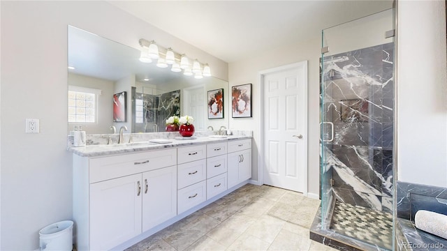 full bath featuring a marble finish shower, double vanity, and a sink