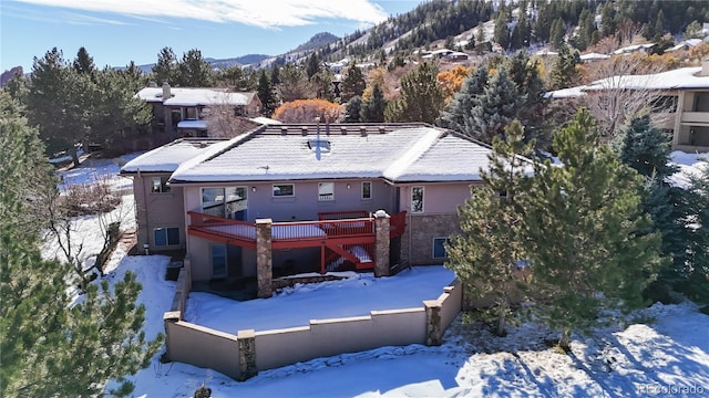 snow covered back of property featuring stairway and a deck with mountain view