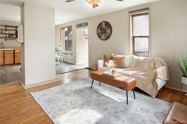 living area with ceiling fan, light wood-style flooring, and a healthy amount of sunlight