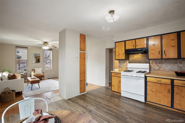 kitchen with light countertops, white gas range oven, dark wood-type flooring, and under cabinet range hood