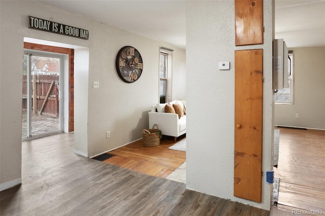 hall with wood finished floors and a textured wall