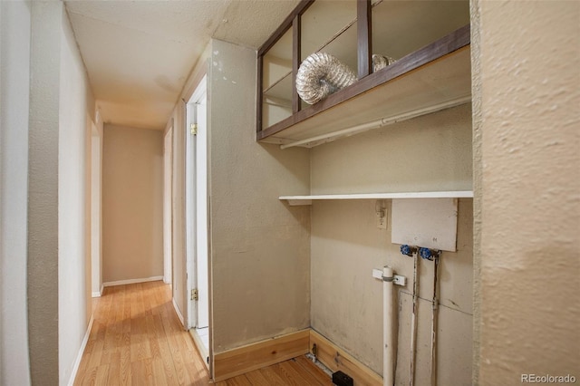 laundry room with baseboards, a textured wall, wood finished floors, and laundry area