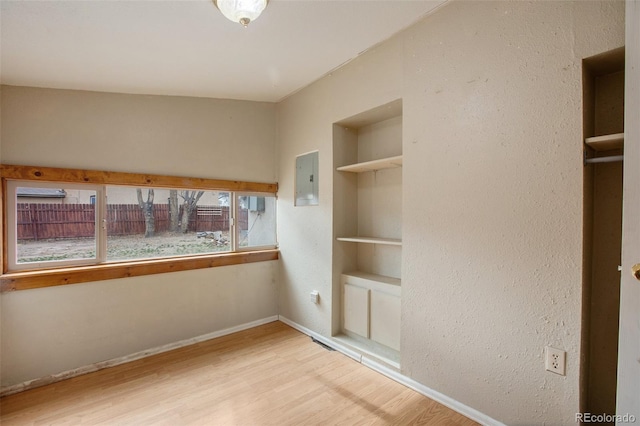 unfurnished bedroom featuring baseboards, wood finished floors, and electric panel