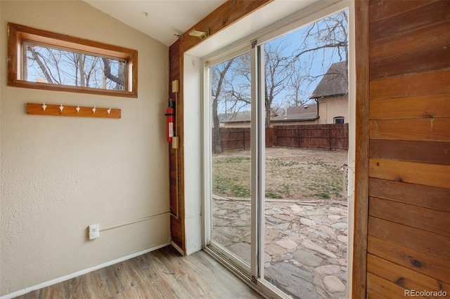 entryway featuring baseboards, wood finished floors, vaulted ceiling, and plenty of natural light