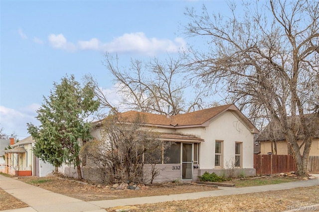 view of front of house with a sunroom, stucco siding, and fence