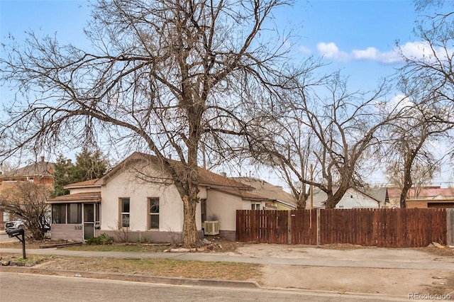view of property exterior featuring stucco siding, a sunroom, central air condition unit, and fence