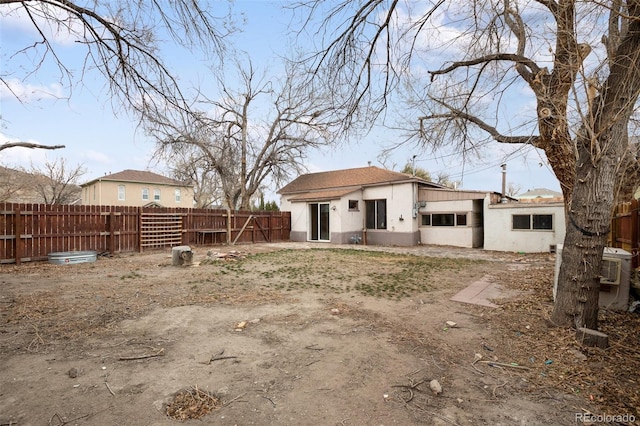 rear view of property featuring a fenced backyard and stucco siding
