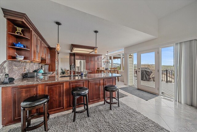 kitchen with decorative backsplash, open shelves, a sink, a peninsula, and high end fridge