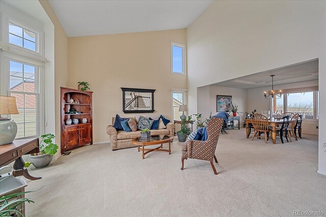 carpeted living room with plenty of natural light, baseboards, a notable chandelier, and high vaulted ceiling