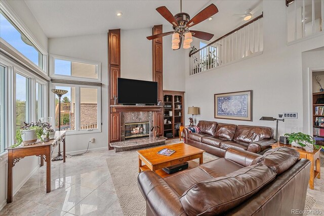 living room with baseboards, a high end fireplace, ceiling fan, and a high ceiling