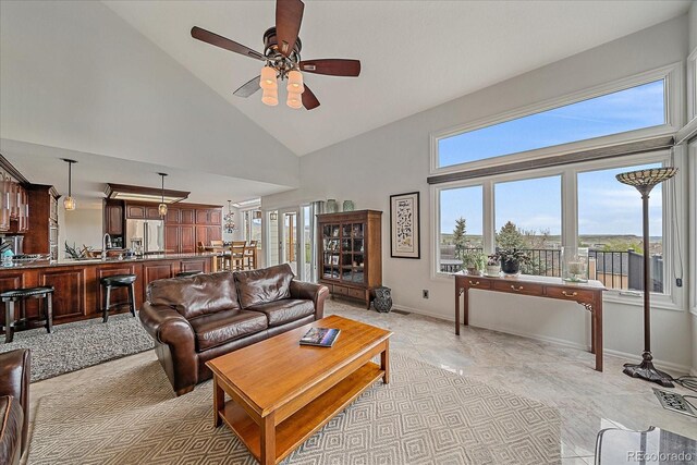 living area with baseboards, high vaulted ceiling, and ceiling fan