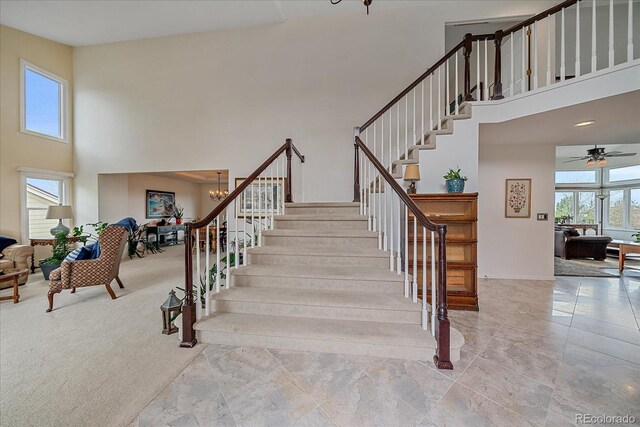 staircase featuring a high ceiling and ceiling fan with notable chandelier