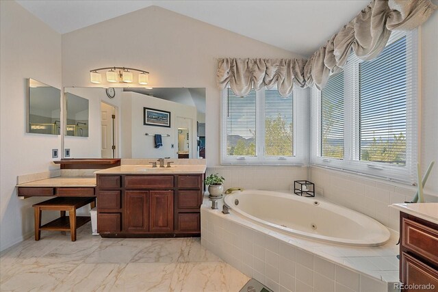 bathroom featuring a whirlpool tub, vaulted ceiling, marble finish floor, and vanity