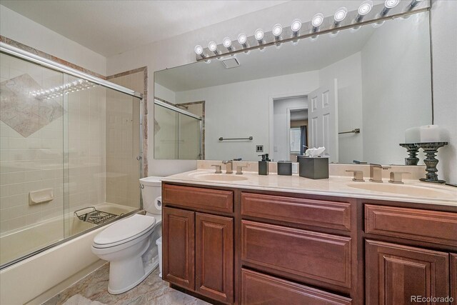 full bathroom with double vanity, toilet, a sink, and shower / bath combination with glass door