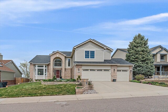 view of front facade featuring driveway, a front yard, a garage, brick siding, and fence