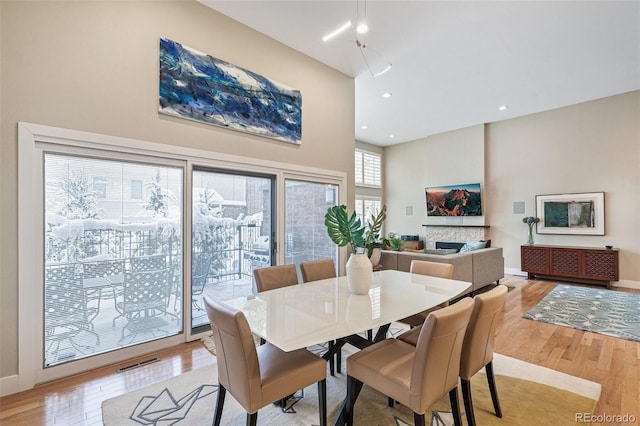 dining space featuring light wood-type flooring and a towering ceiling