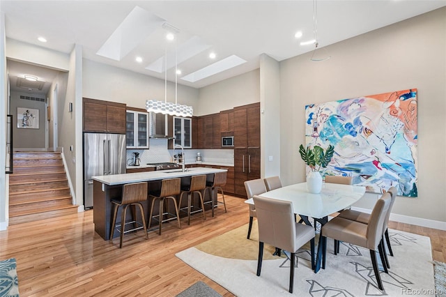 dining space featuring sink, a towering ceiling, and light wood-type flooring