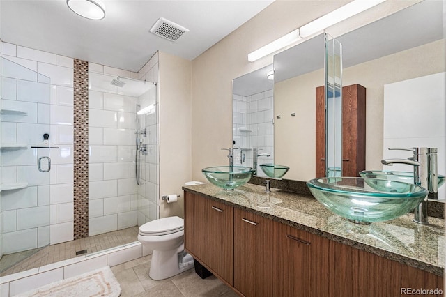 bathroom with toilet, walk in shower, vanity, and tile patterned flooring