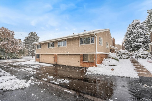 snow covered back of property featuring a garage