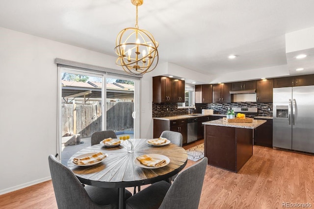 12648 W Virginia Ave, Lakewood, CO 80228 - kitchen featuring decorative backsplash, dark brown cabinetry, a center island, a notable chandelier, and stainless steel appliances