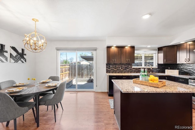 12648 W Virginia Ave, Lakewood, CO 80228 - kitchen with dark brown cabinets, a chandelier, plenty of natural light, and tasteful backsplash