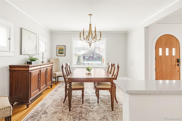 dining space featuring light wood finished floors, ornamental molding, and a chandelier