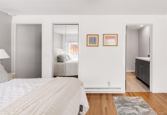 bedroom featuring baseboards, light wood-style flooring, and baseboard heating