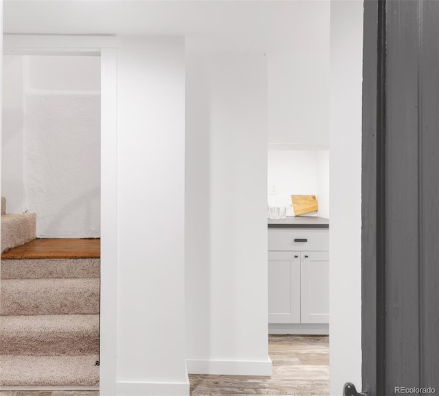 stairway with a bar, wood finished floors, and baseboards