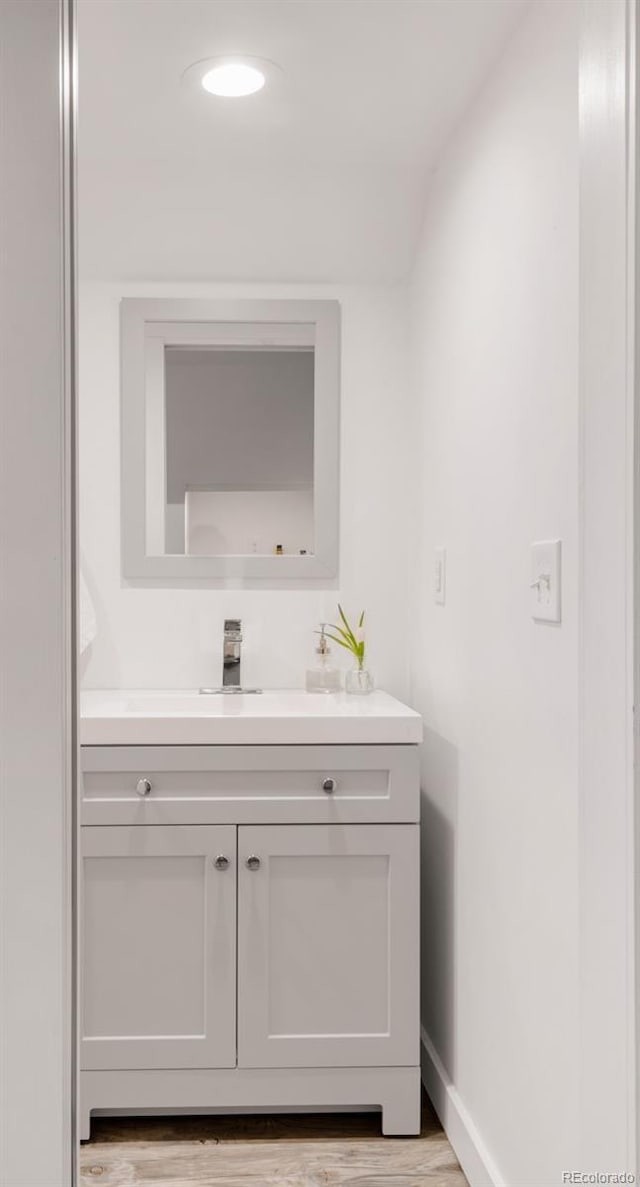 bathroom featuring vanity, baseboards, and wood finished floors