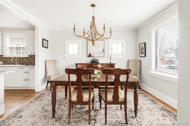 dining space featuring a wealth of natural light, a chandelier, light wood-style flooring, and ornamental molding